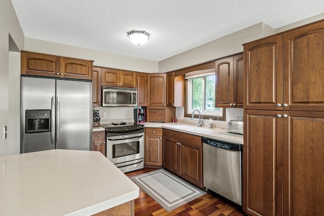 4133 88th Ave NE, Blaine, MN 55014 - kitchen with appliances with stainless steel finishes, dark wood-style flooring, light countertops, brown cabinetry, and a textured ceiling