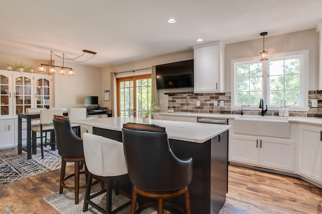 15544 60th Ave S, Riverton Twp, MN 56547 - kitchen with white cabinets, backsplash, a kitchen breakfast bar, light wood-style floors, and recessed lighting