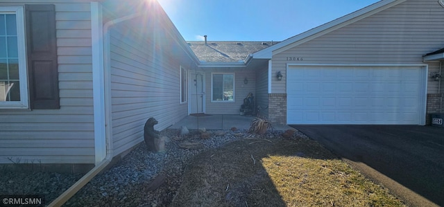 13046 Brookside Ln N, Rogers, MN 55374 - property entrance featuring asphalt driveway, an attached garage, and roof with shingles