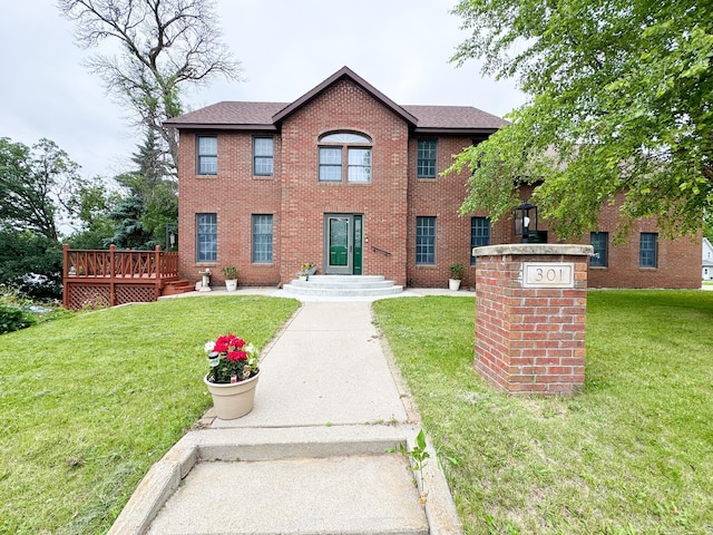 301 4th Ave SE, Pelican Rapids, MN 56572 - colonial house with brick siding, a front lawn, a deck, and roof with shingles