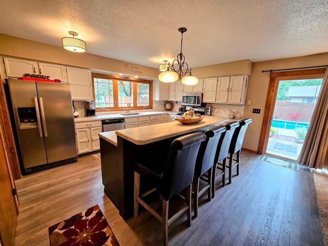 902 6th Ave SE, Pipestone, MN 56164 - kitchen with stainless steel appliances, a textured ceiling, light countertops, white cabinets, and decorative backsplash