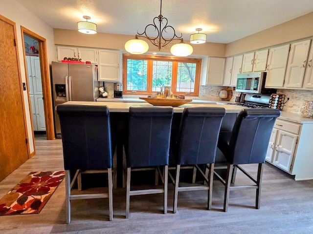 902 6th Ave SE, Pipestone, MN 56164 - kitchen featuring appliances with stainless steel finishes, backsplash, light countertops, and white cabinets