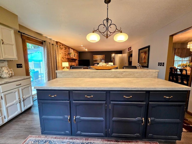 902 6th Ave SE, Pipestone, MN 56164 - kitchen with white cabinetry, blue cabinetry, open floor plan, a chandelier, and light countertops