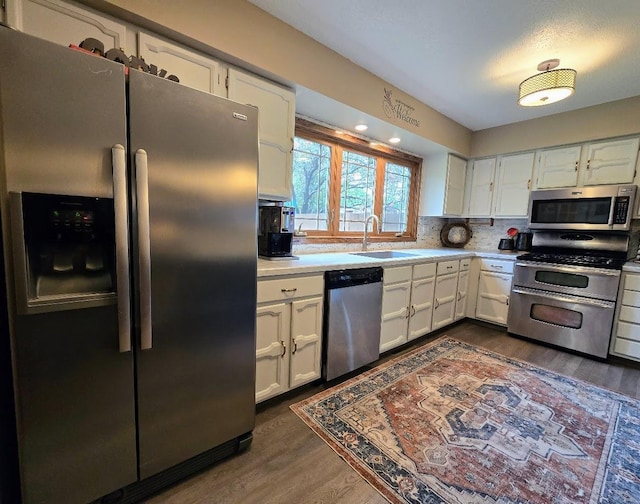 902 6th Ave SE, Pipestone, MN 56164 - kitchen featuring appliances with stainless steel finishes, light countertops, dark wood-type flooring, and white cabinets