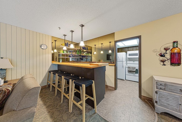 9700 Portland Ave S Unit 237, Bloomington, MN 55420 - kitchen featuring white appliances, wood counters, a breakfast bar area, a peninsula, and a textured ceiling