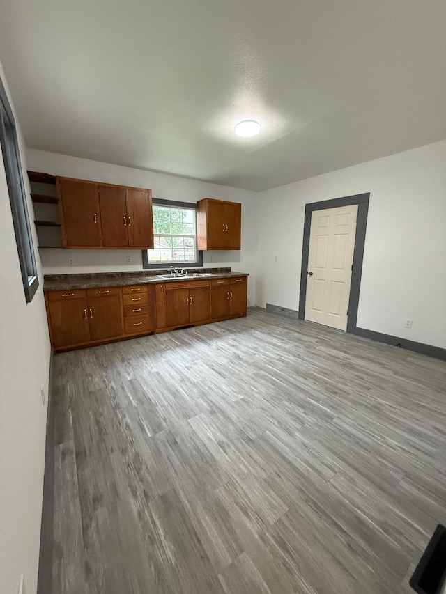 409 4th St W, Canby, MN 56220 - kitchen featuring light wood-style floors, brown cabinetry, dark countertops, open shelves, and open floor plan
