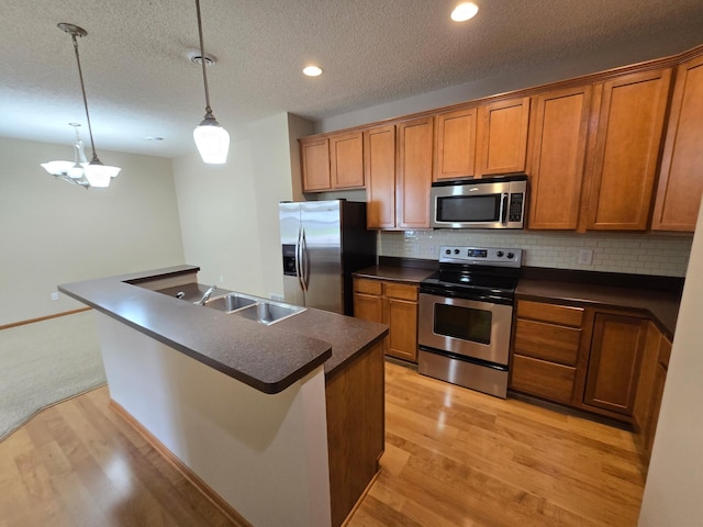 703 10th St S, Buffalo, MN 55313 - kitchen with stainless steel appliances, dark countertops, brown cabinetry, recessed lighting, and a textured ceiling