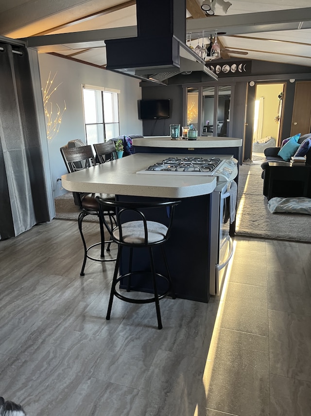 1323 Pine Tree Dr, Maplewood, MN 55119 - kitchen with stainless steel range with gas stovetop, a center island, lofted ceiling, light countertops, and a kitchen breakfast bar