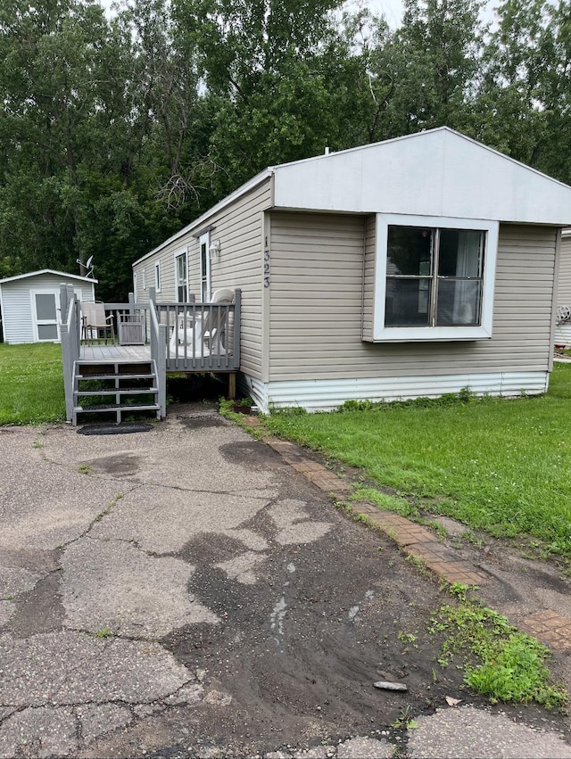 1323 Pine Tree Dr, Maplewood, MN 55119 - view of side of property featuring a wooden deck, a yard, and a storage shed