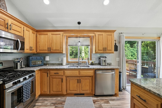 22615 Janero Ave N, Forest Lake, MN 55025 - kitchen with appliances with stainless steel finishes, vaulted ceiling, light stone countertops, light wood-type flooring, and backsplash