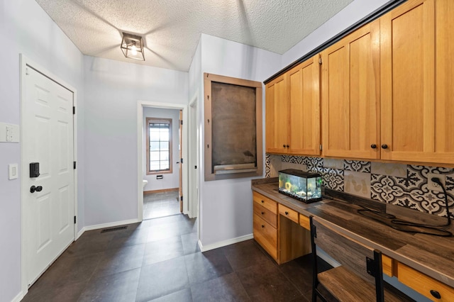 4802 102nd Trl N, Brooklyn Park, MN 55443 - kitchen with tasteful backsplash, built in study area, butcher block countertops, dark tile patterned flooring, and a textured ceiling