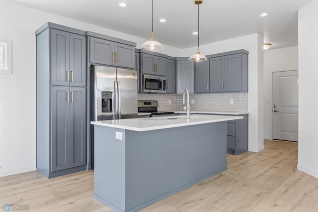 7326 28th St S, Fargo, ND 58104 - kitchen featuring stainless steel appliances, light wood-style floors, decorative backsplash, light countertops, and a kitchen island with sink