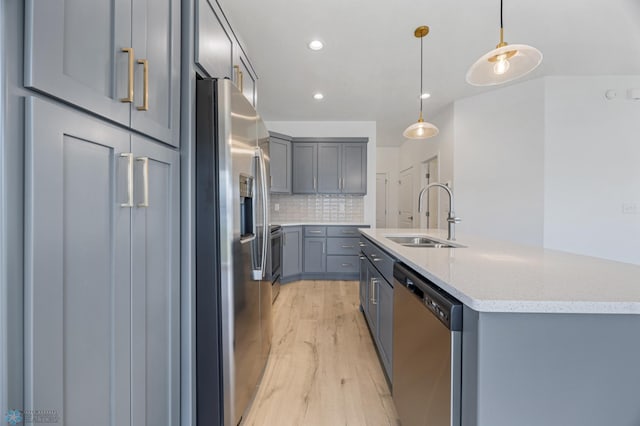 7326 28th St S, Fargo, ND 58104 - kitchen with stainless steel appliances, gray cabinetry, light wood-style flooring, backsplash, and a center island with sink