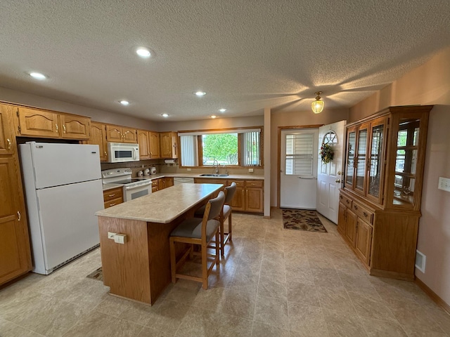 1508 Terrance Cir NE, New Prague, MN 56071 - kitchen featuring white appliances, a center island, recessed lighting, a textured ceiling, and light countertops