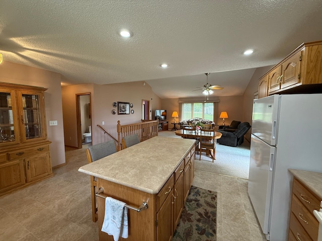 1508 Terrance Cir NE, New Prague, MN 56071 - kitchen with freestanding refrigerator, lofted ceiling, light countertops, ceiling fan, and a textured ceiling