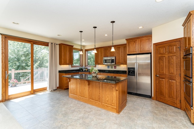 3262 Jade Ct NE, Rochester, MN 55906 - kitchen featuring appliances with stainless steel finishes, brown cabinets, a center island, hanging light fixtures, and dark stone countertops