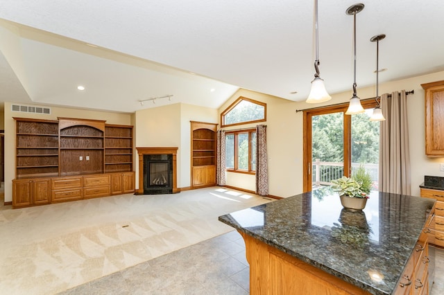 3262 Jade Ct NE, Rochester, MN 55906 - kitchen featuring a fireplace with flush hearth, a kitchen island, pendant lighting, light colored carpet, and dark stone countertops