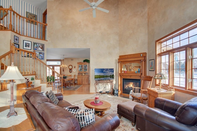 19319 380th St, Erhards Grove Twp, MN 56534 - living room featuring a high ceiling, stairs, ceiling fan, a glass covered fireplace, and a chandelier