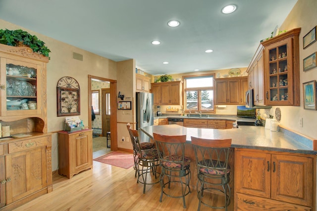 19319 380th St, Erhards Grove Twp, MN 56534 - kitchen with appliances with stainless steel finishes, a peninsula, light wood-type flooring, recessed lighting, and glass insert cabinets
