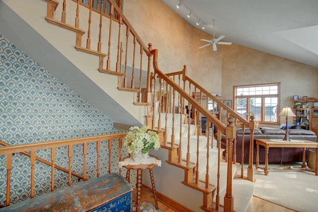 19319 380th St, Erhards Grove Twp, MN 56534 - stairway with wood finished floors, a ceiling fan, rail lighting, high vaulted ceiling, and wallpapered walls