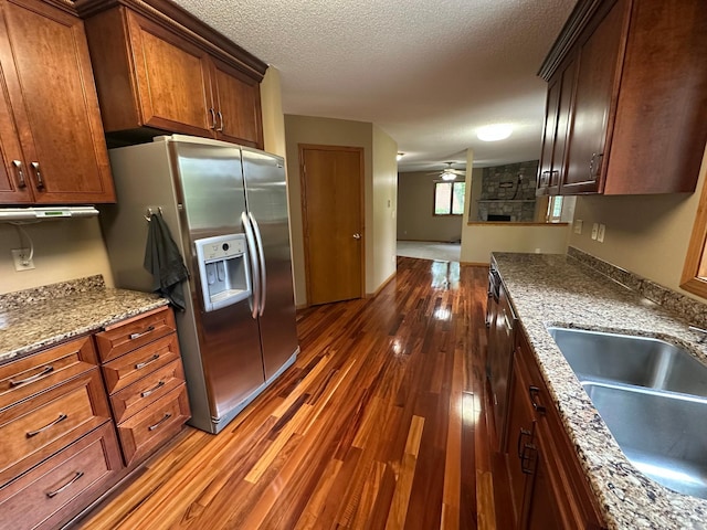 1702 15th St SW, Willmar, MN 56201 - kitchen featuring stainless steel fridge with ice dispenser, dark wood-style floors, a ceiling fan, light stone counters, and a textured ceiling