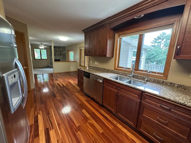 1702 15th St SW, Willmar, MN 56201 - kitchen with stainless steel appliances, dark wood finished floors, a large fireplace, ceiling fan, and light stone counters