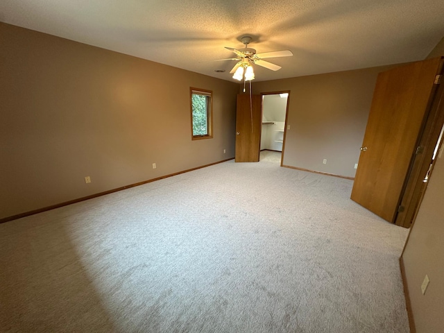 1702 15th St SW, Willmar, MN 56201 - unfurnished bedroom with light colored carpet, a textured ceiling, a ceiling fan, and a walk in closet