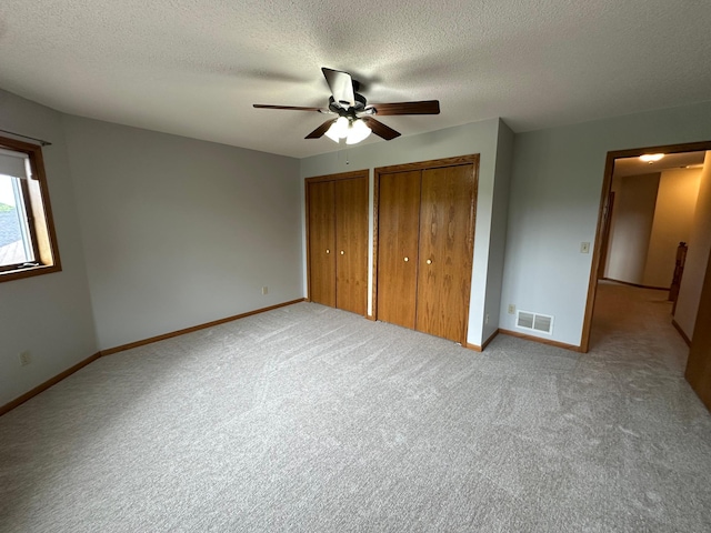 1702 15th St SW, Willmar, MN 56201 - unfurnished bedroom with multiple closets, carpet flooring, a textured ceiling, and ceiling fan