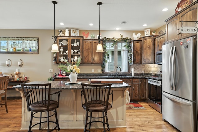 129 Highland Cir, Dassel, MN 55325 - kitchen with appliances with stainless steel finishes, a center island, light wood finished floors, pendant lighting, and a breakfast bar area