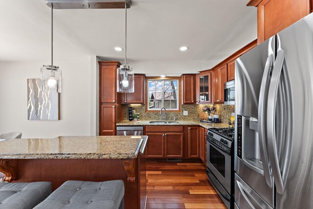 8473 Kentucky Ct N, Brooklyn Park, MN 55445 - kitchen featuring stainless steel appliances, dark wood-style flooring, brown cabinetry, backsplash, and light stone counters
