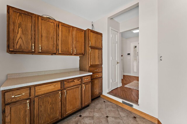8473 Kentucky Ct N, Brooklyn Park, MN 55445 - kitchen with light countertops, brown cabinetry, and light tile patterned floors