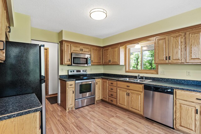 13838 Glendale Trl, Savage, MN 55378 - kitchen with stainless steel appliances, light wood-type flooring, dark countertops, and a textured ceiling