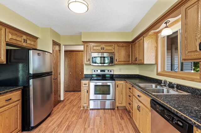 13838 Glendale Trl, Savage, MN 55378 - kitchen featuring stainless steel appliances, light wood-style floors, dark countertops, and a textured ceiling