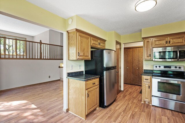 13838 Glendale Trl, Savage, MN 55378 - kitchen with stainless steel appliances, light wood-style flooring, dark countertops, and a textured ceiling