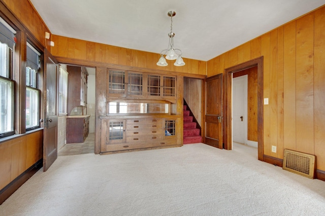3736 Park Ave, Minneapolis, MN 55407 - unfurnished room featuring a chandelier, wood walls, plenty of natural light, stairway, and light carpet
