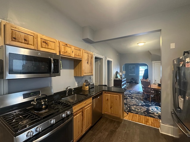 713 2nd St NE, Minneapolis, MN 55413 - kitchen featuring appliances with stainless steel finishes, dark wood-style flooring, arched walkways, a peninsula, and dark stone countertops