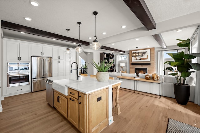 1162 Woods Creek Dr, Delano, MN 55328 - kitchen with appliances with stainless steel finishes, beam ceiling, light wood-style flooring, open floor plan, and light countertops