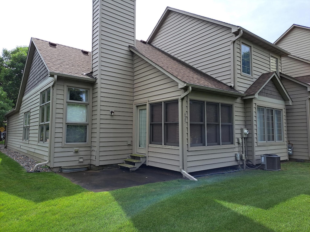 625 Sullivan Dr NE, Columbia Heights, MN 55421 - back of property with entry steps, a chimney, a shingled roof, and a lawn