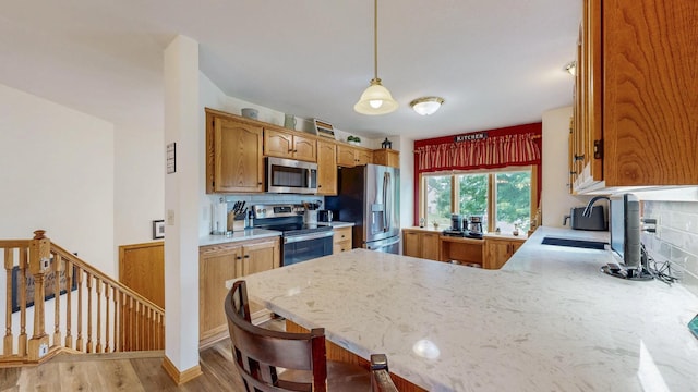 1057 John And Mary Dr SE, Chatfield, MN 55923 - kitchen with appliances with stainless steel finishes, a peninsula, backsplash, light wood-type flooring, and decorative light fixtures
