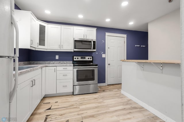 1709 13th Ave S, Fargo, ND 58103 - kitchen with appliances with stainless steel finishes, white cabinetry, light wood-type flooring, glass insert cabinets, and recessed lighting
