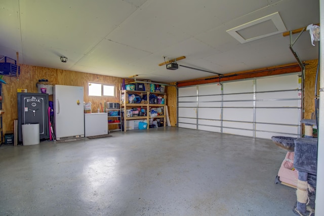 111 W Ave, Ottertail, MN 56571 - garage with freestanding refrigerator, a garage door opener, fridge, and wooden walls