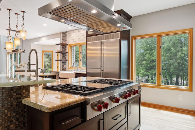 5401 River Oak Dr, Savage, MN 55378 - kitchen featuring wall chimney exhaust hood, stainless steel appliances, light stone counters, decorative light fixtures, and light wood-style floors