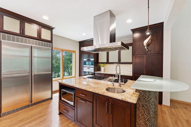 5401 River Oak Dr, Savage, MN 55378 - kitchen featuring stainless steel appliances, island exhaust hood, light wood-style floors, decorative backsplash, and dark brown cabinetry
