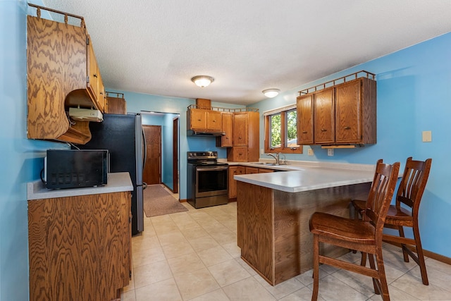 655 48th Ave, Goodview, MN 55987 - kitchen featuring stainless steel electric range oven, black microwave, a peninsula, brown cabinetry, and under cabinet range hood