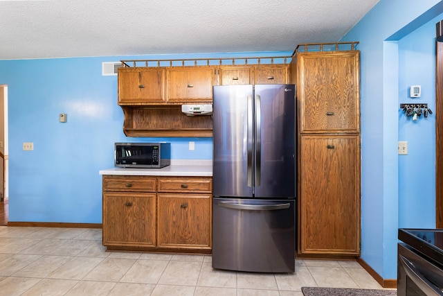 655 48th Ave, Goodview, MN 55987 - kitchen featuring appliances with stainless steel finishes, brown cabinetry, light countertops, a textured ceiling, and light tile patterned floors