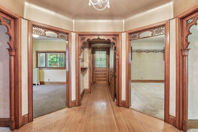 1323 Keston St, Saint Paul, MN 55108 - corridor with radiator, light colored carpet, a chandelier, and light wood-style flooring
