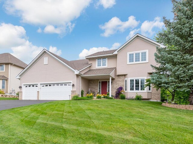 1632 Seashell Ln, Waconia, MN 55387 - traditional-style house with an attached garage, a front lawn, asphalt driveway, brick siding, and roof with shingles