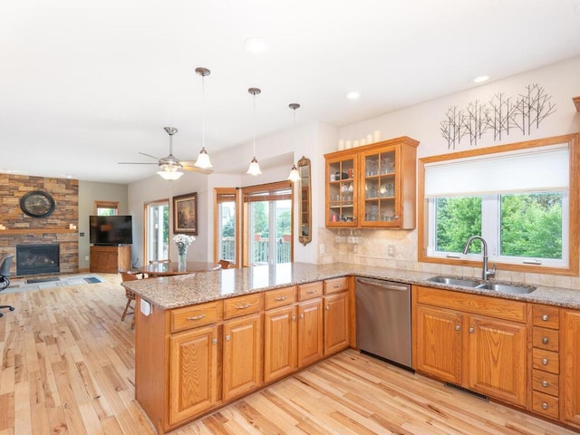 1632 Seashell Ln, Waconia, MN 55387 - kitchen with stainless steel dishwasher, light wood-type flooring, a peninsula, a fireplace, and light stone countertops