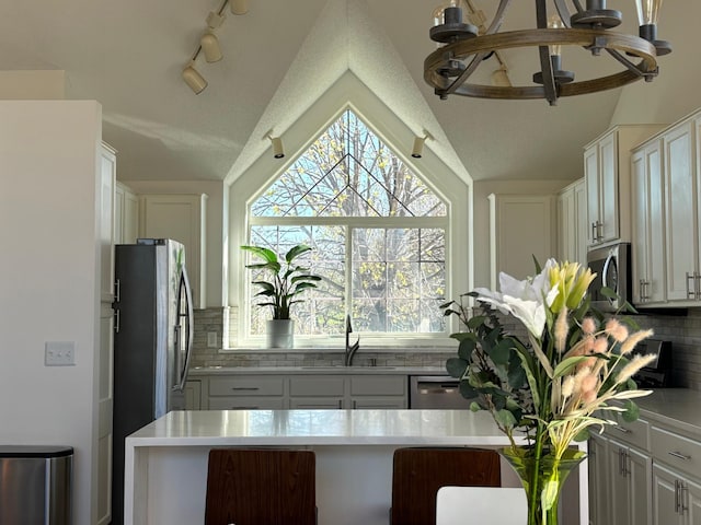 23120 Gardner Ave, Rogers, MN 55374 - kitchen featuring lofted ceiling, decorative backsplash, stainless steel appliances, white cabinetry, and a chandelier