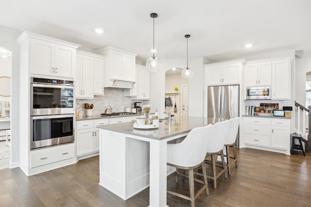 10914 23rd St NE, Saint Michael, MN 55376 - kitchen featuring appliances with stainless steel finishes, decorative backsplash, arched walkways, dark wood-type flooring, and white cabinets